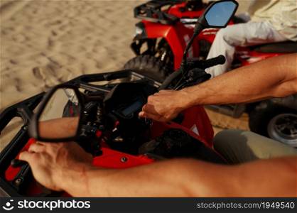 Man rides on atv in desert, closeup view on hands. Male persons on quad bikes, sandy race, dune safari in hot sunny day, 4x4 extreme adventure, quad-biking. Man rides on atv in desert, closeup view on hands