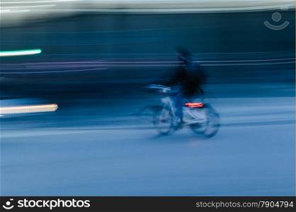 Man Riding a Bicycle in a Blurred City Scene