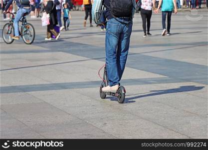 Man riding a kick scooter at the city square