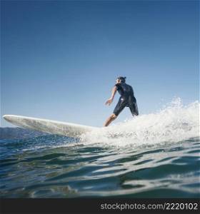 man riding his surfboard side view