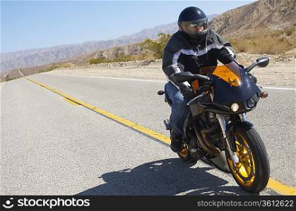 Man riding motorcycle on desert road