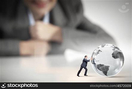 Man rolling planet. Businesswoman looking at miniature of businessman rolling planet