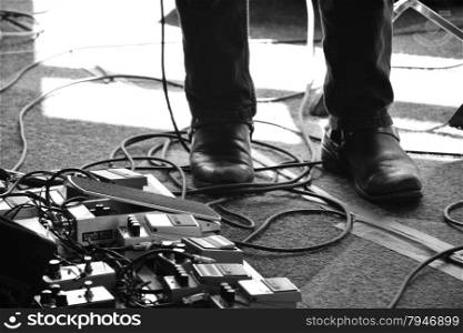 man&rsquo;s feet next to a guitar pedal board