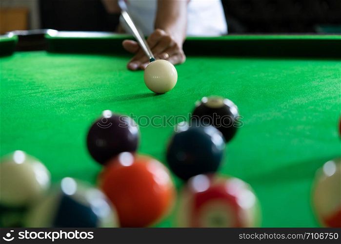 Man&rsquo;s hand and Cue arm playing snooker game or preparing aiming to shoot pool balls on a green billiard table
