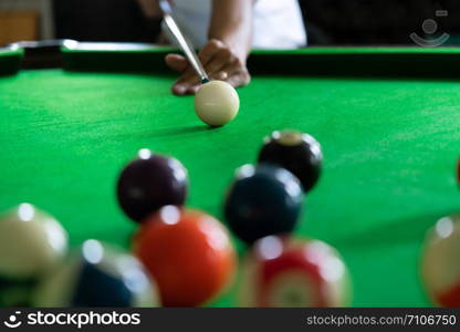 Man&rsquo;s hand and Cue arm playing snooker game or preparing aiming to shoot pool balls on a green billiard table