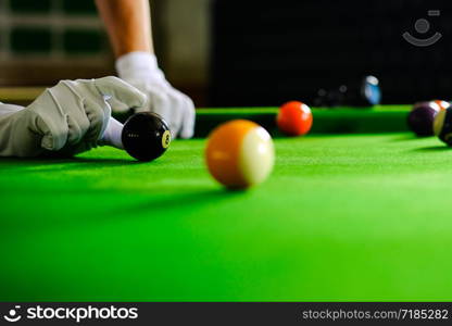 Man&rsquo;s hand and Cue arm playing snooker game or preparing aiming to shoot pool balls on a green billiard table. Colorful snooker balls on green frieze