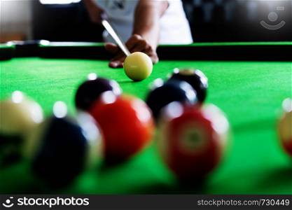 Man's hand and Cue arm playing snooker game or preparing aiming to shoot pool balls on a green billiard table