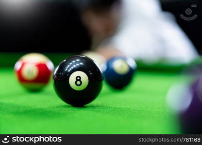 Man's hand and Cue arm playing snooker game or preparing aiming to shoot pool balls on a green billiard table