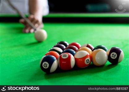 Man's hand and Cue arm playing snooker game or preparing aiming to shoot pool balls on a green billiard table