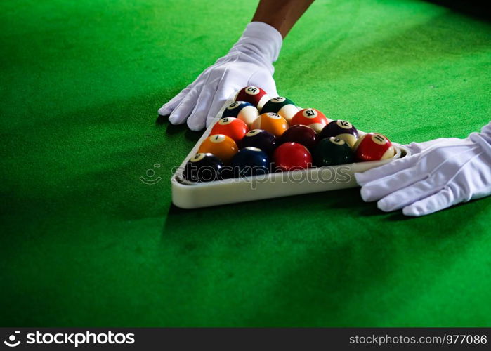 Man's hand and Cue arm playing snooker game or preparing aiming to shoot pool balls on a green billiard table. Colorful snooker balls on green frieze