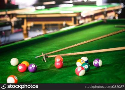 Man's hand and Cue arm playing snooker game or preparing aiming to shoot pool balls on a green billiard table. Colorful snooker balls on green frieze