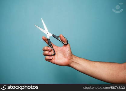 Man&rsquo;s hand is holding a pair of open scissors