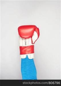 man's hand is wearing a red leather boxing glove on a gray background, sports backdrop