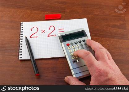 Man&rsquo;s hand pushes the button on the calculator solving the equation