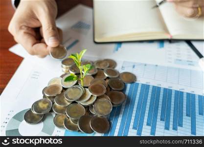 Man's hand putting coins stack for business finance accounting yield plant growing or investment for saving finance growing concept