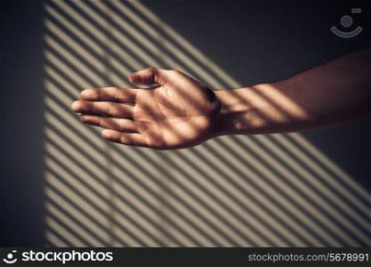 Man&rsquo;s hand with shadows being cast from blinds