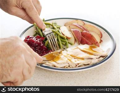 Man&rsquo;s hands eating a delicious turkey dinner for Thanksgiving or other meal.