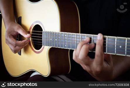 man&rsquo;s hands playing acoustic guitar