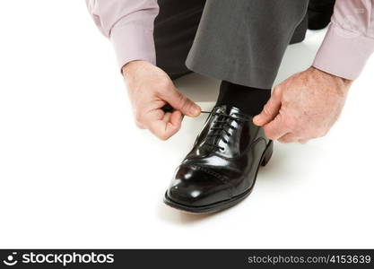 Man&rsquo;s hands tying shoelace of his new oxford shoes. Isolated on white.