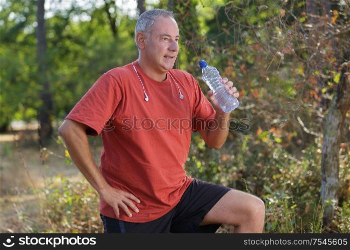 man runner running in forest and drinking water