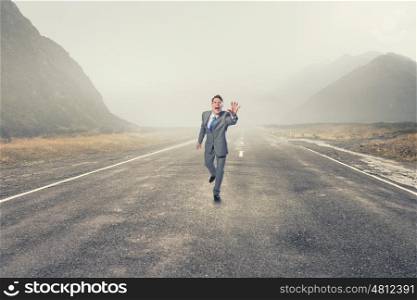 Man running and reaching hand. Young screaming businessman running on asphalt road
