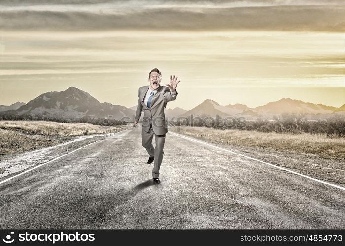 Man running and reaching hand. Young screaming businessman running on asphalt road