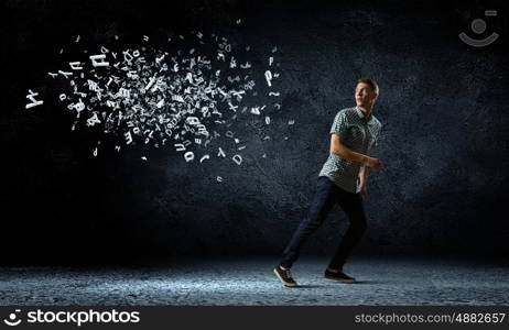 Man running away. Funny image of young man trying to escape from flying letters