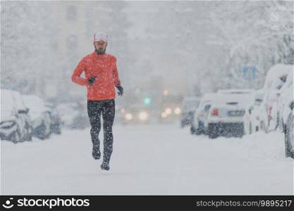 Man runs in the downtown street of a snowy city