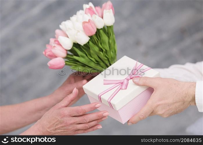 man s hand giving birthday gift tulip flowers bouquet his wife