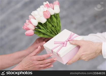 man s hand giving birthday gift tulip flowers bouquet his wife