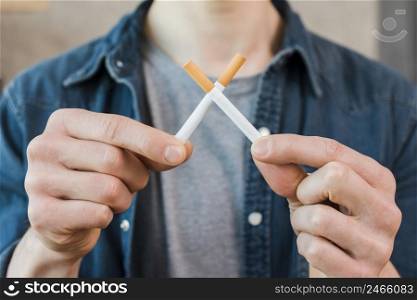 man s hand holding crossed cigarettes
