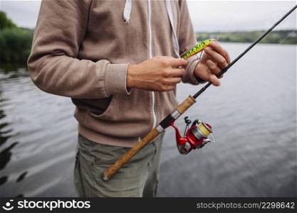 man s hand holding fishing lure rod
