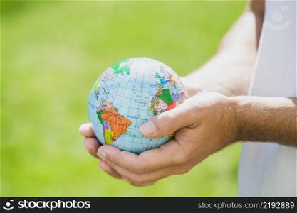 man s hand holding small globe