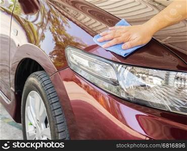 Man's hand is cleaning and waxing the car