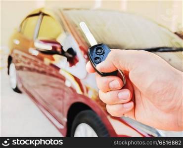 Man's hand is holding remote key pointing to his car