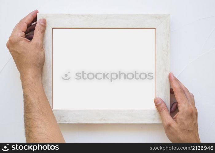 man s hand placing white picture frame wall