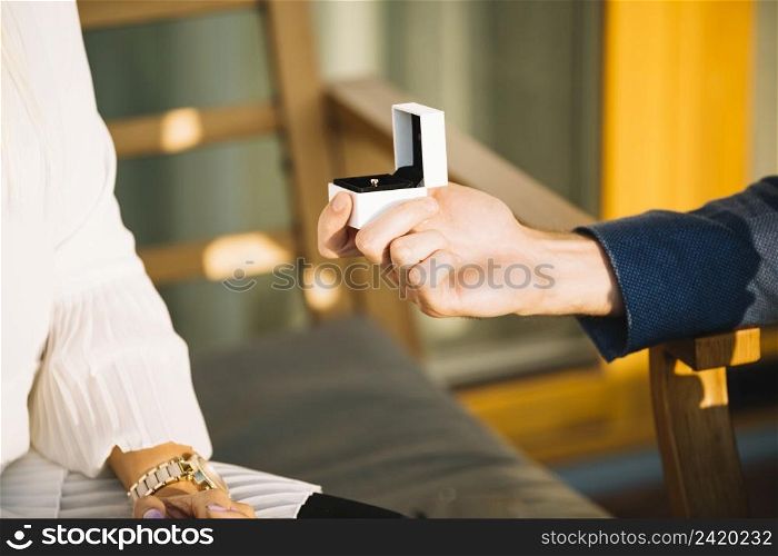 man s hand showing engagement ring box her girlfriend