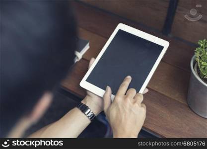 man's hand using digital tablet on wooden table, selective focus and vintage tone
