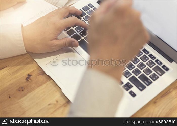 man's hand working with laptop computer notebook for working concept, selective focus and vintage tone