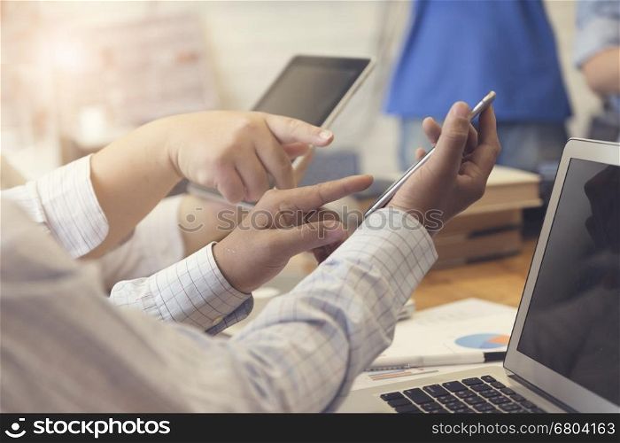 man's hand working with mobile phone, tablet, business document and laptop computer notebook for working concept, selective focus and vintage tone