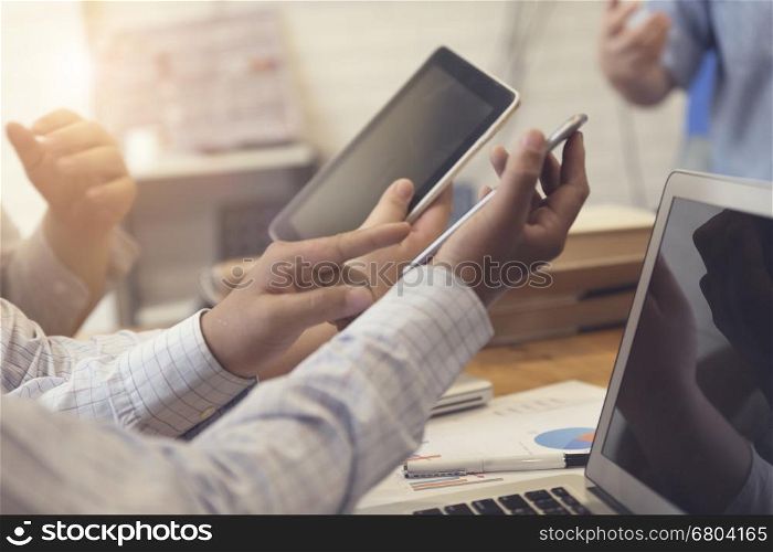 man's hand working with mobile phone, tablet, business document and laptop computer notebook for working concept, selective focus and vintage tone