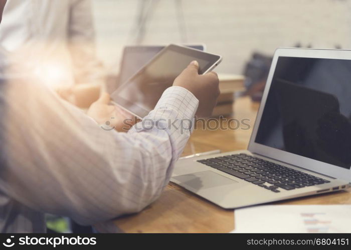 man's hand working with tablet, business document and laptop computer notebook for working concept, selective focus and vintage tone