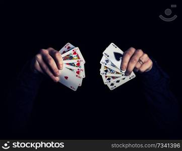Man’s hands holding five playing cards each over. Poker combinatons on black background