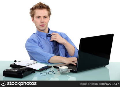 Man sat at desk loosening tie
