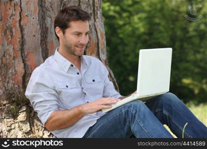 Man sat by tree with laptop