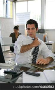 Man sat in office adjusting his tie