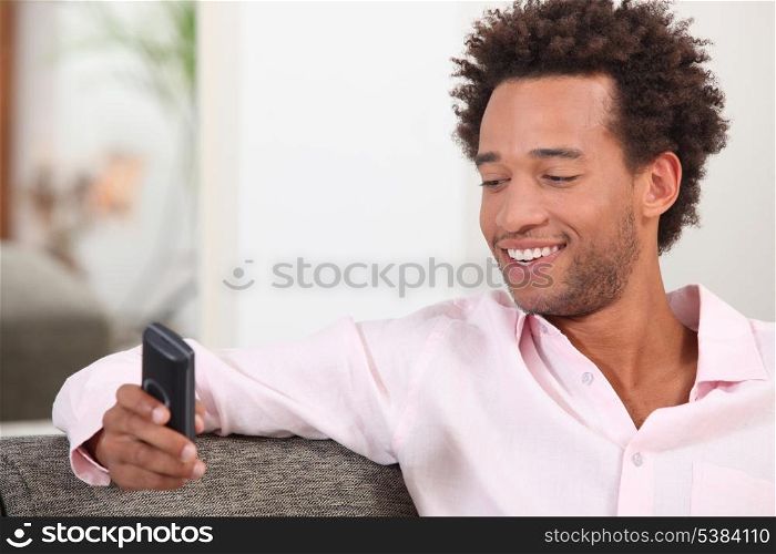 Man sat on sofa sending text message