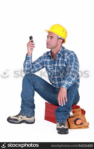 Man sat on tool box sending text message