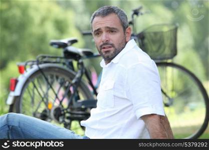 Man sat relaxing next to bicycle