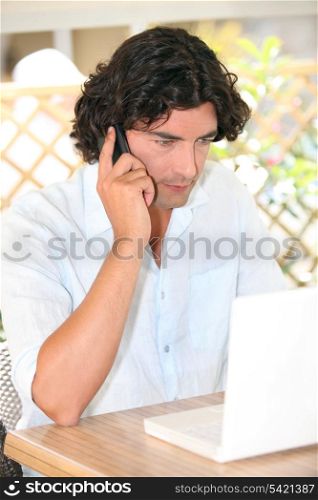 Man sat with laptop and telephone on terrace